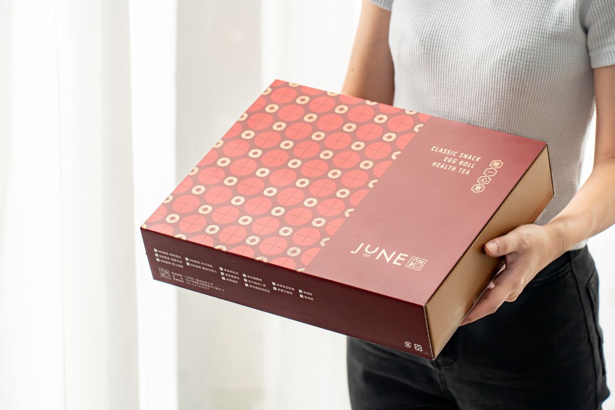手持六月初一紅色精美禮盒正面，JUNE 1ST品牌識別清楚，台北商務急送首選